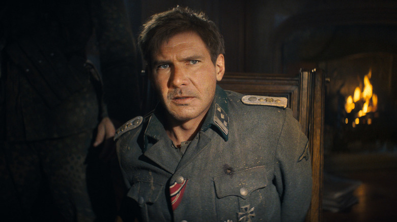 Indiana Jones sitting in a chair in front of a fire place wearing a uniform