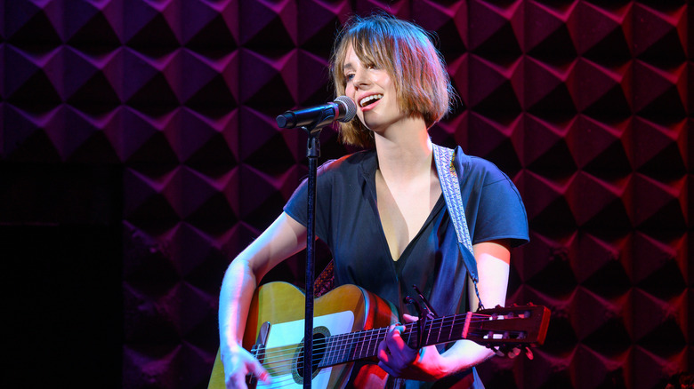 Maya Hawke playing guitar at a concert