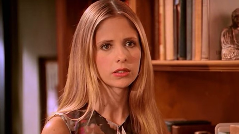 Buffy standing next to a book shelf