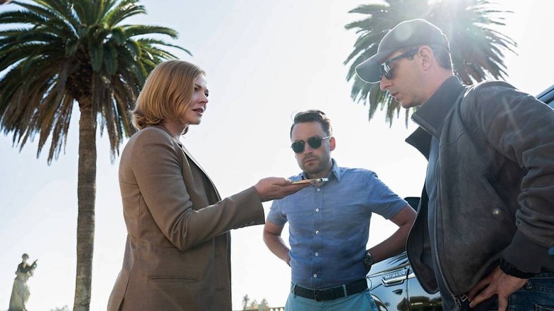 Shiv, Kendall, and Roman stand beneath palm trees