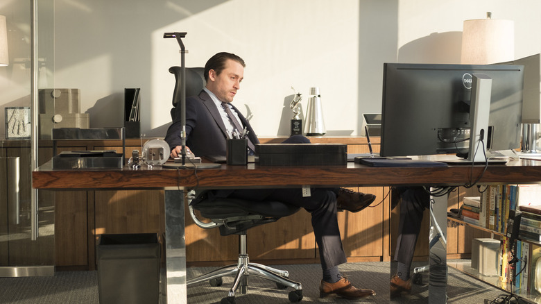 Roman Roy sitting behind desk