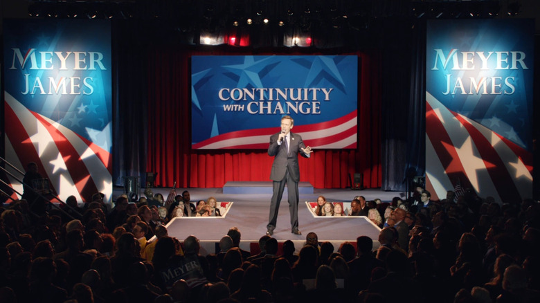 Tom James stands in front of a sign that reads Continuity With Changes