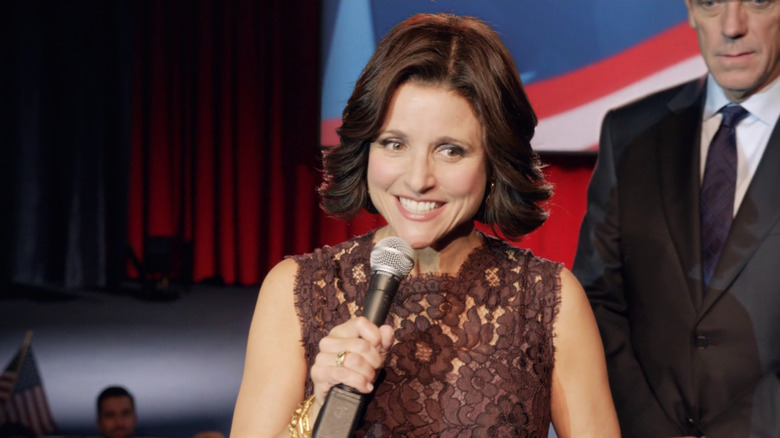 Selina Meyer holds a microphone in front of Tom James