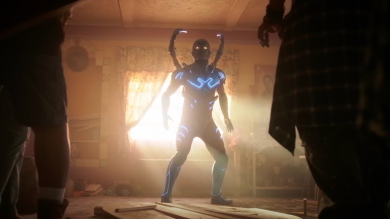 Blue Beetle stands in the Reyes kitchen in "Blue Beetle" (2023)