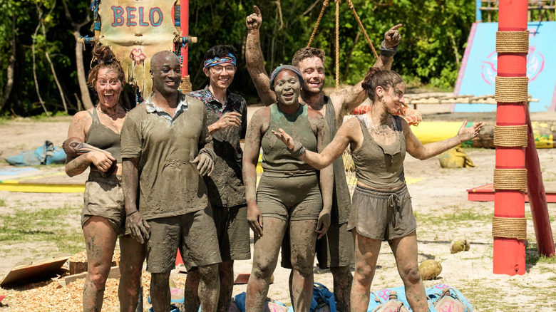 Survivor tribe covered in mud smiling gesturing