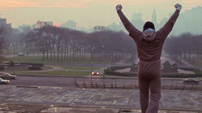 Rocky Balboa raising his arms after running up stairs