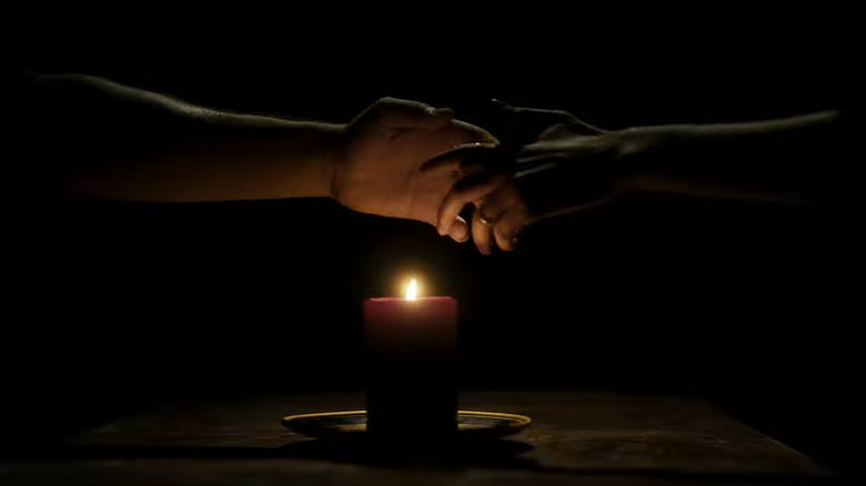 hands clasping over candle