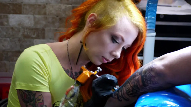 Megan Massacre tattooing a customer