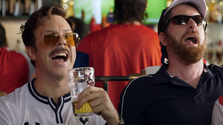 Ted Lasso and Coach Beard drinking beer and shouting