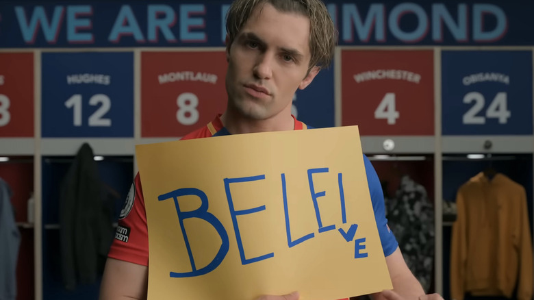 Jamie Tartt holds up a believe sign