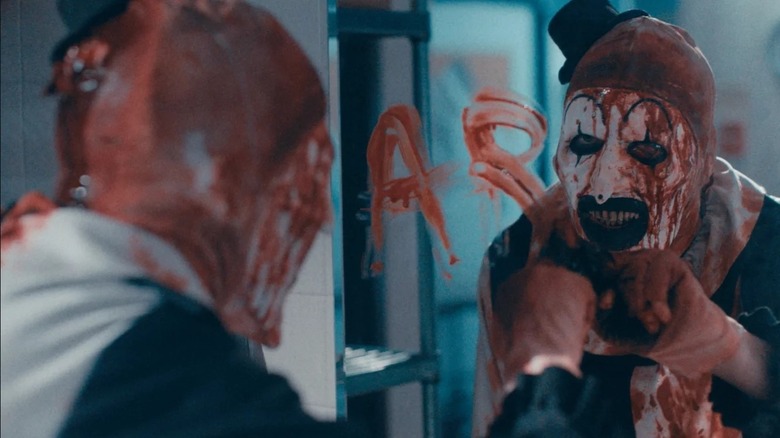 Art the Clown writes his name on a mirror in blood