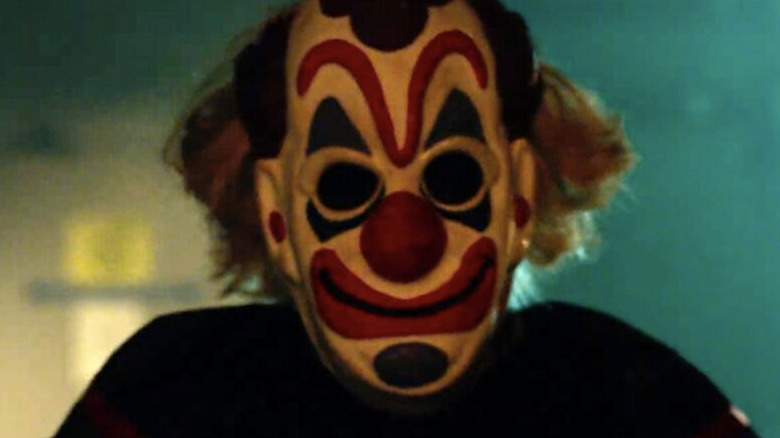 Clown Mask stands in dim light