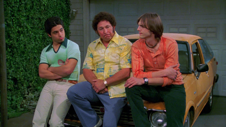 Fez, Bob, and Kelso sitting on car