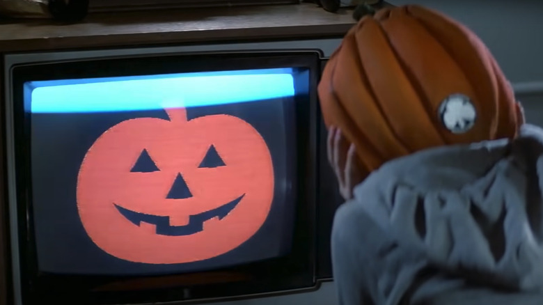 pumpkin mask child watches TV