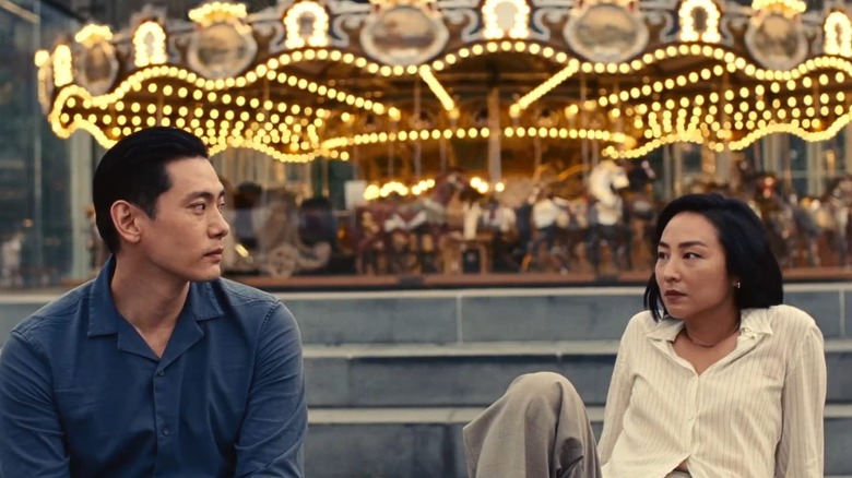 Nora and Hae Sung sitting in front of a carousel in "Past Lives"