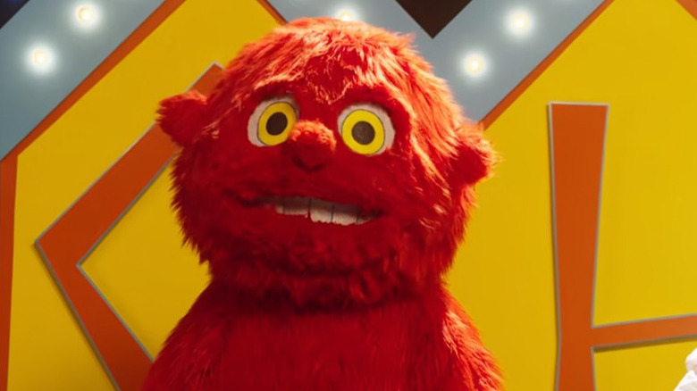 A man in a red furry suit stares ahead 