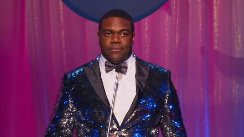 Sam Richardson looks annoyed holding a microphone 