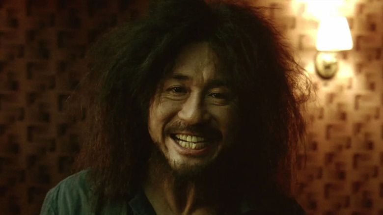 A disheveled Dae-su smiles into the camera in "Old Boy" (2003)