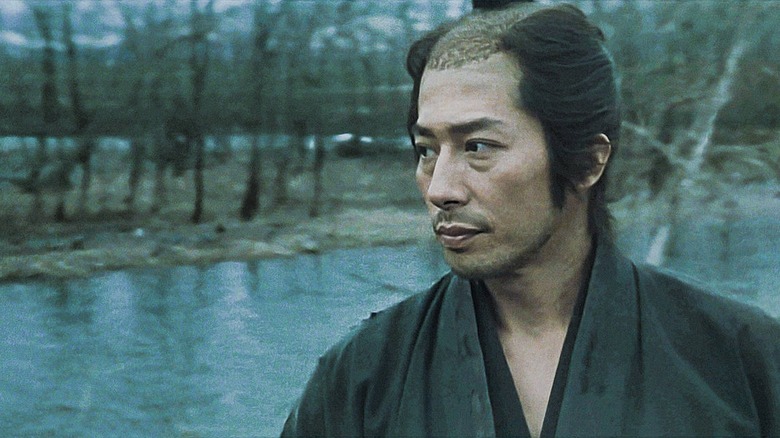 Seibei Iguchi standing by a body of water in The Twilight Samurai