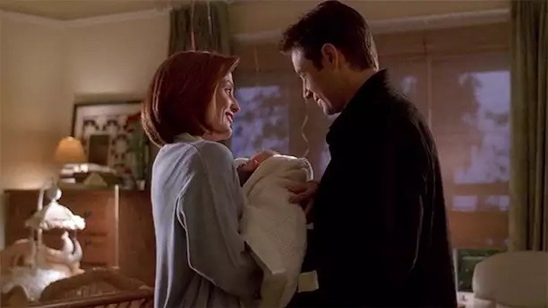 Scully handing baby to Mulder