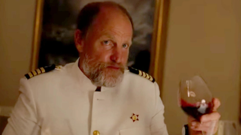 Woody Harrelson holds a glass of wine in Triangle of Sadness