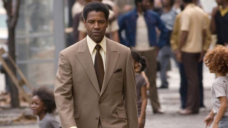 Lucas walks down a NY street in a tan suit.