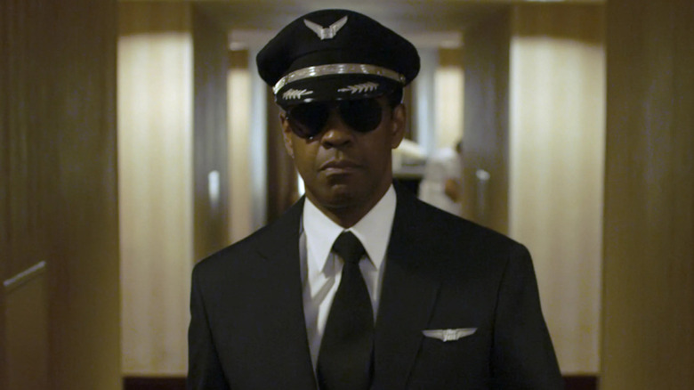 Captain Whitaker walks forward down a hotel hallway.