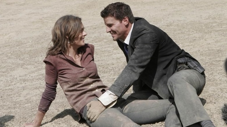 Booth and Bones smiling at each other on the ground