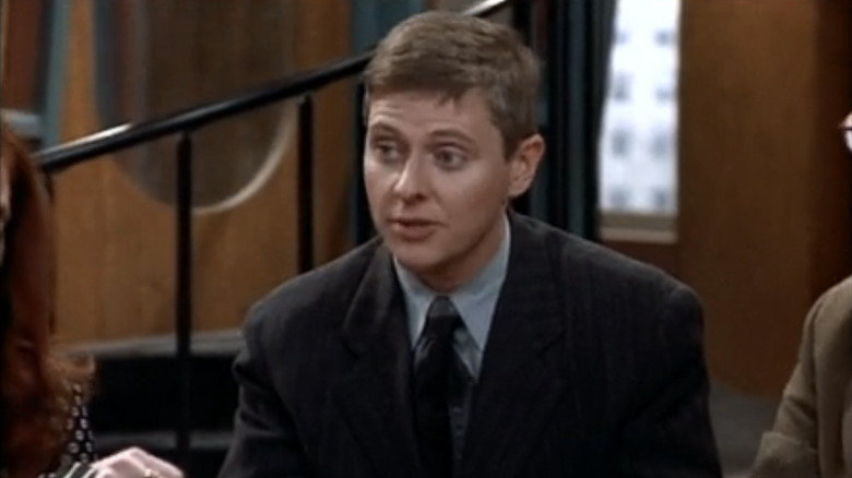 Dave Foley sits at a table on  "NewsRadio"