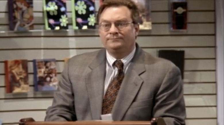 Stephen Root stands at a podium on "NewsRadio"