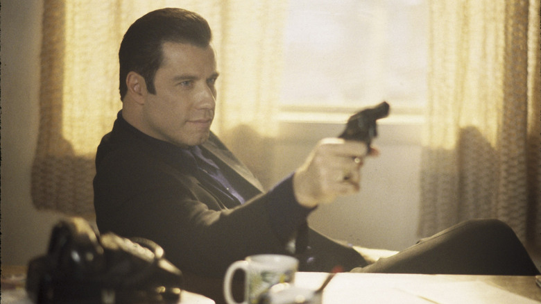 Chili sits behind a desk, holding a gun, in "Get Shorty" (1995)