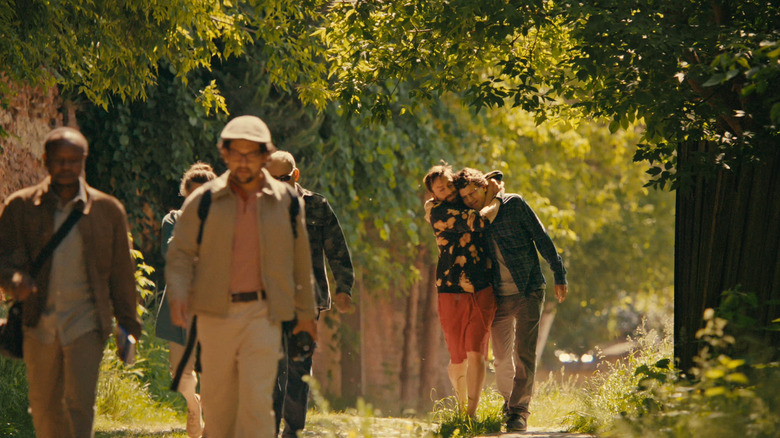 Benji hugs David walking with a tour group in "A Real Pain" (2024)