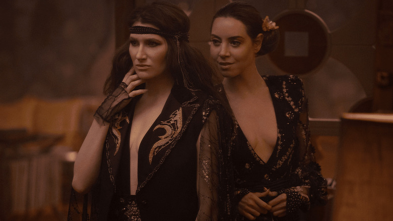 Agatha and Rio dressed in 70s glam watching the rest of the coven (who are off-screen)