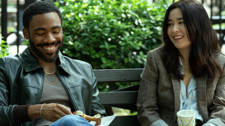 John and Jane Smith laughing with each other over a snack on an NYC park bench