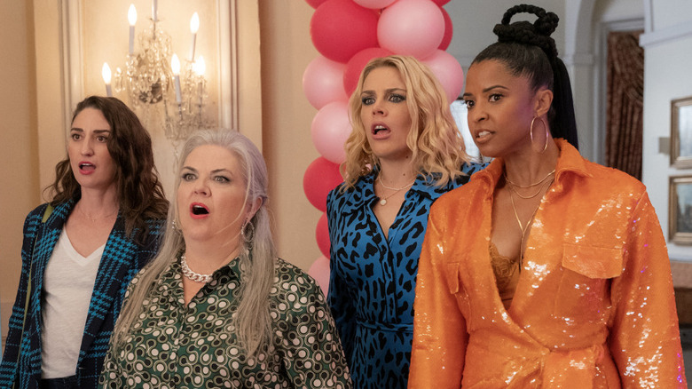 The members of Girls5eva (L to R: Dawn, Gloria, Summer, Wickie) standing together and looking surprised by something off-screen