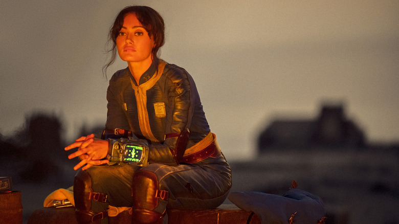 Lucy sitting in front of a bright fire in "Fallout"