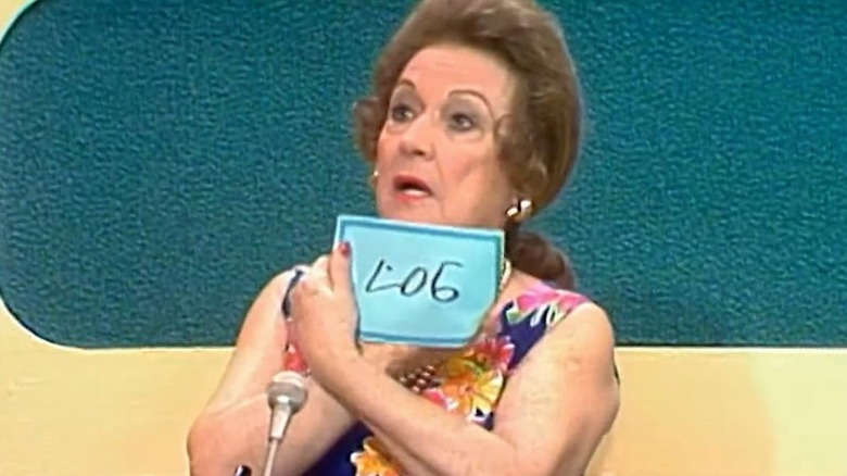 A woman holds a blue paper that reads "log"