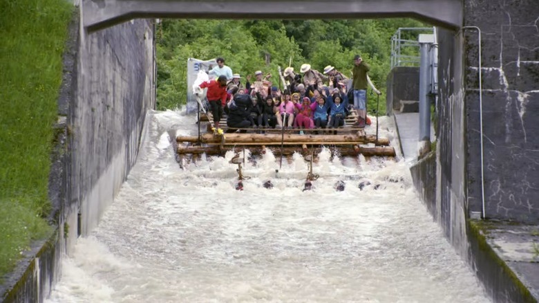 The Amazing Race Season 34 contestants riding a large raft down a stream