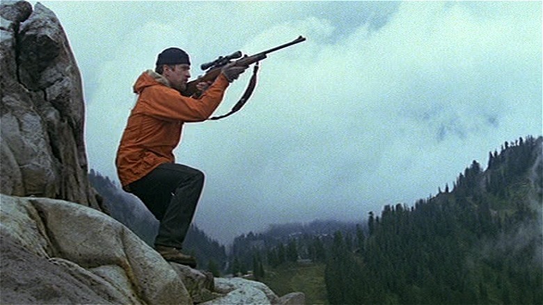 Mike standing on a cliff aiming gun