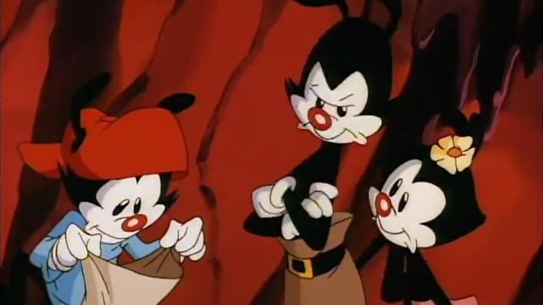 Wakko looks into a bag while Yakko and Dot stand by looking annoyed