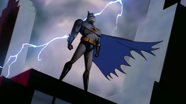 Batman stands atop a building as lighting flashes behind him