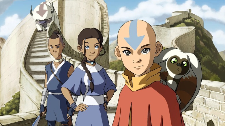 Aang, Katara, and Sokka standing on a huge wall as Appa watches on