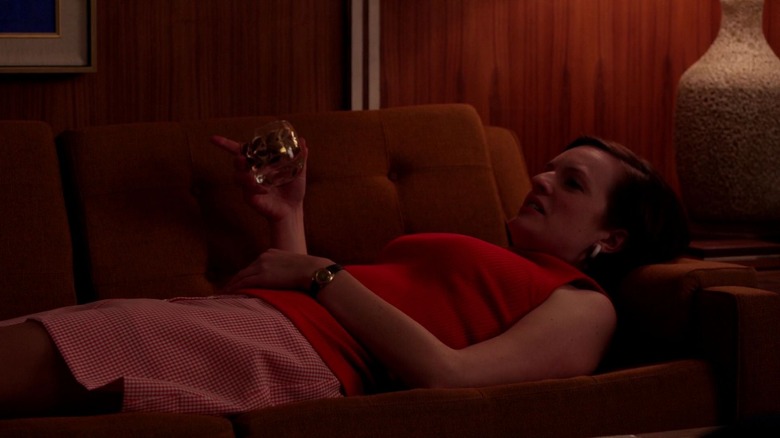 Peggy lies on the couch, smoking and drinking