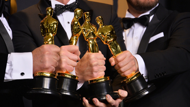 Four Oscars being placed together by the winners
