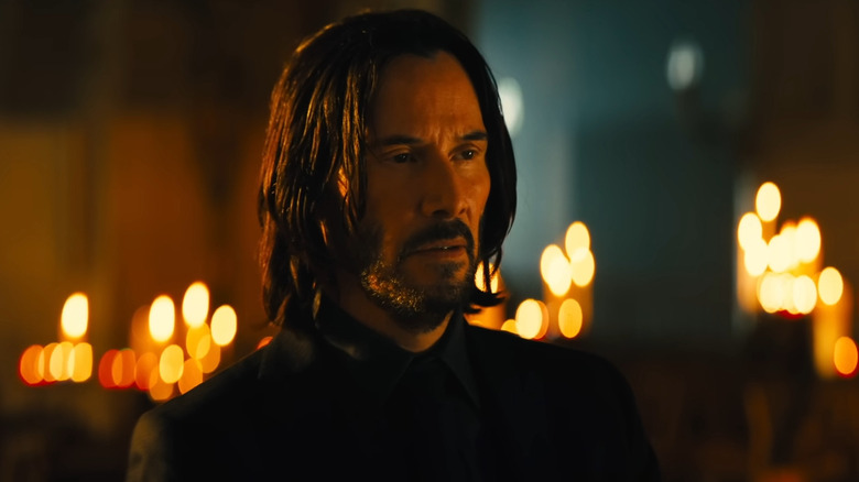 John Wick surrounded by candles and neon light