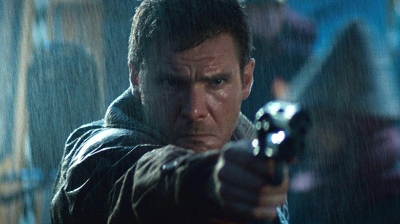 Deckard holds a gun in rain