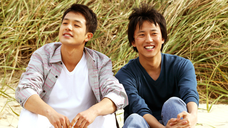 Su-min and Jae-min sitting on the beach together smiling