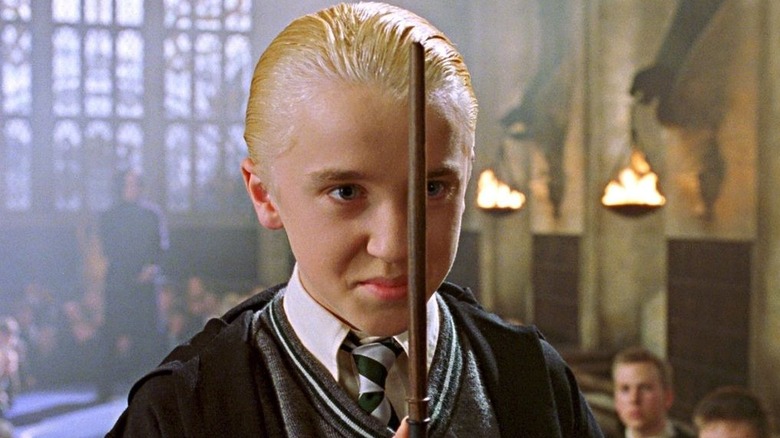 Draco holding wand to face