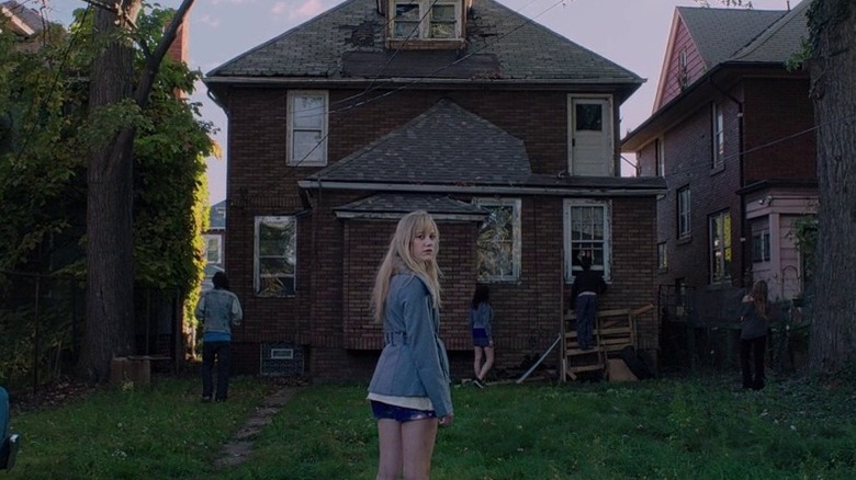 Blonde girl standing by decrepit house