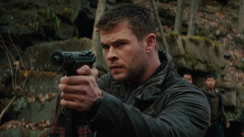 Chris Hemsworth points gun in woods